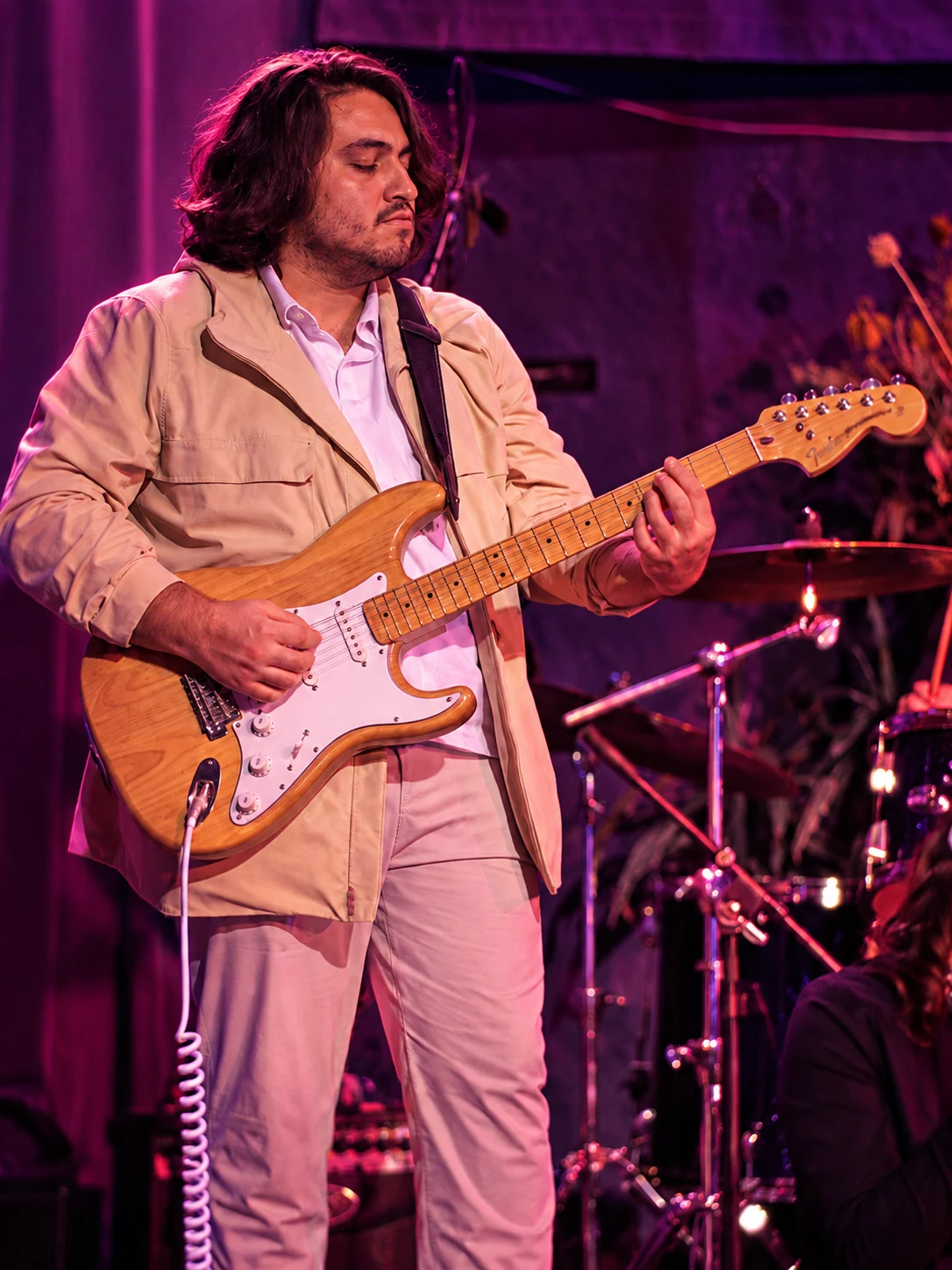 Guitarrista tocando bajo luces magenta